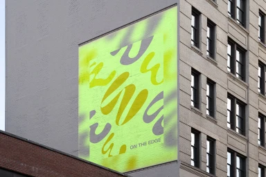 Large yellow and grey abstract graphic mural on a concrete building exterior wall for On the Edge brand identity.