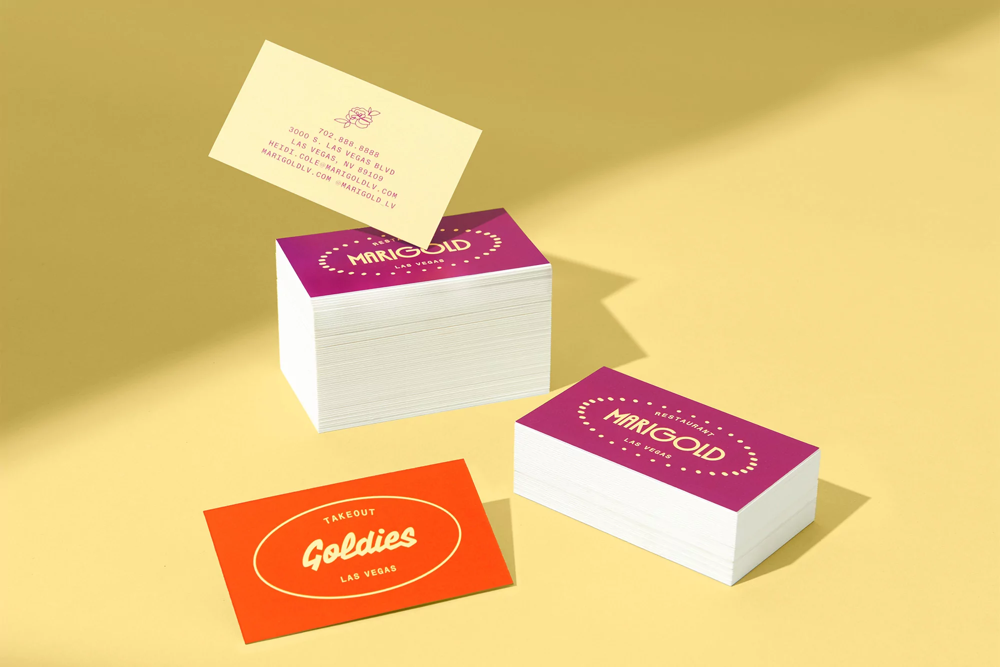 Close-up of Marigold restaurant business cards in bright yellow, orange, and magenta colors. Perfect for restaurants and marketing.