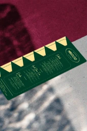 Green Marigold restaurant menu resting on concrete and deep red textured fabric with soft shadows