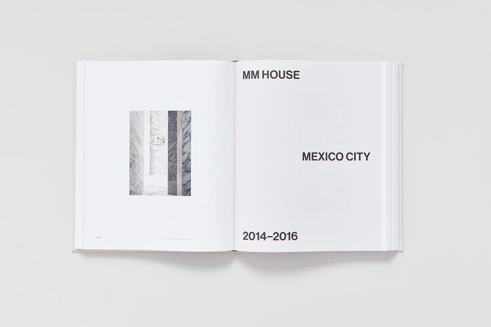 Open book featuring an image of a marble wall and the text 'MM House, Mexico City, 2014-2016,' set against a clean, white backdrop.