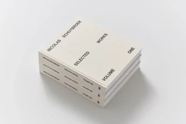 A stack of three hardcover books with cream covers and black typography resting on a plain white surface