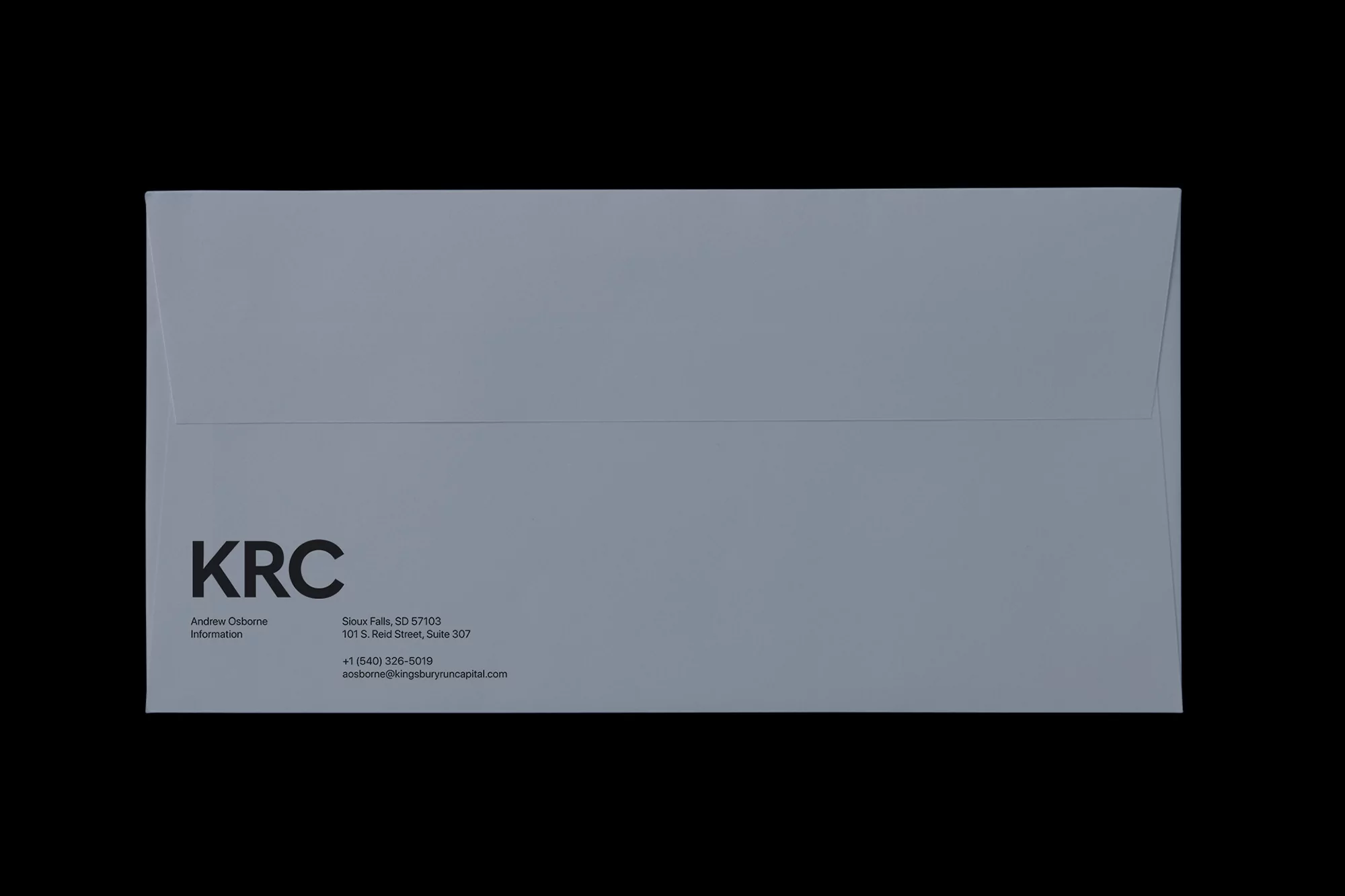 Promotional image featuring a grey envelope with printed text on a black background, showcasing the KRC brand, and business information.