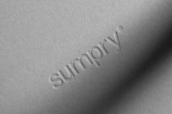 The word 'sumpry' embossed on a textured gray paper surface.