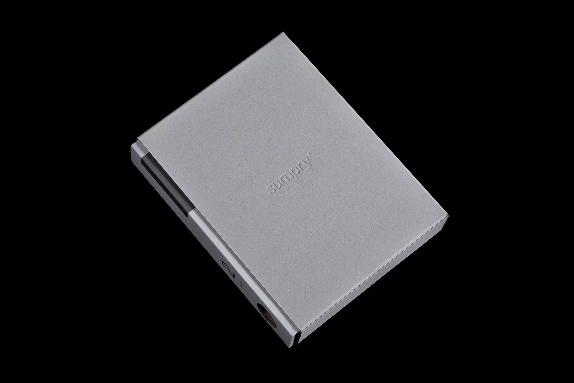 Elevated studio shot of a sleek, gray metal card case with embossed logo, set against a stark black background, emphasizing its modern design.