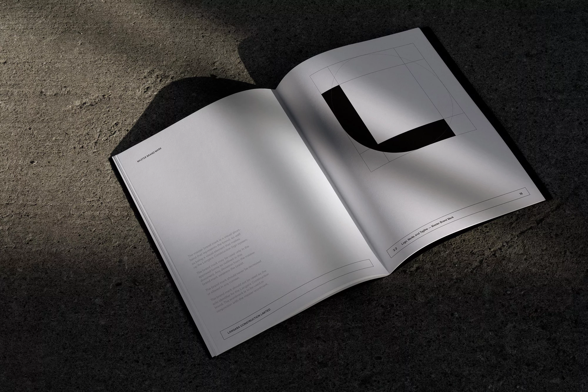 Open book on a gray surface featuring a black graphic design on the right page and text on the left, under neutral lighting.