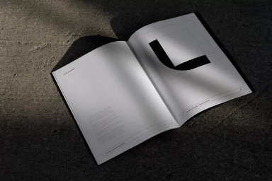 An open brand identity guidelines book displaying typography and geometric logo marks on a dark textured concrete surface.