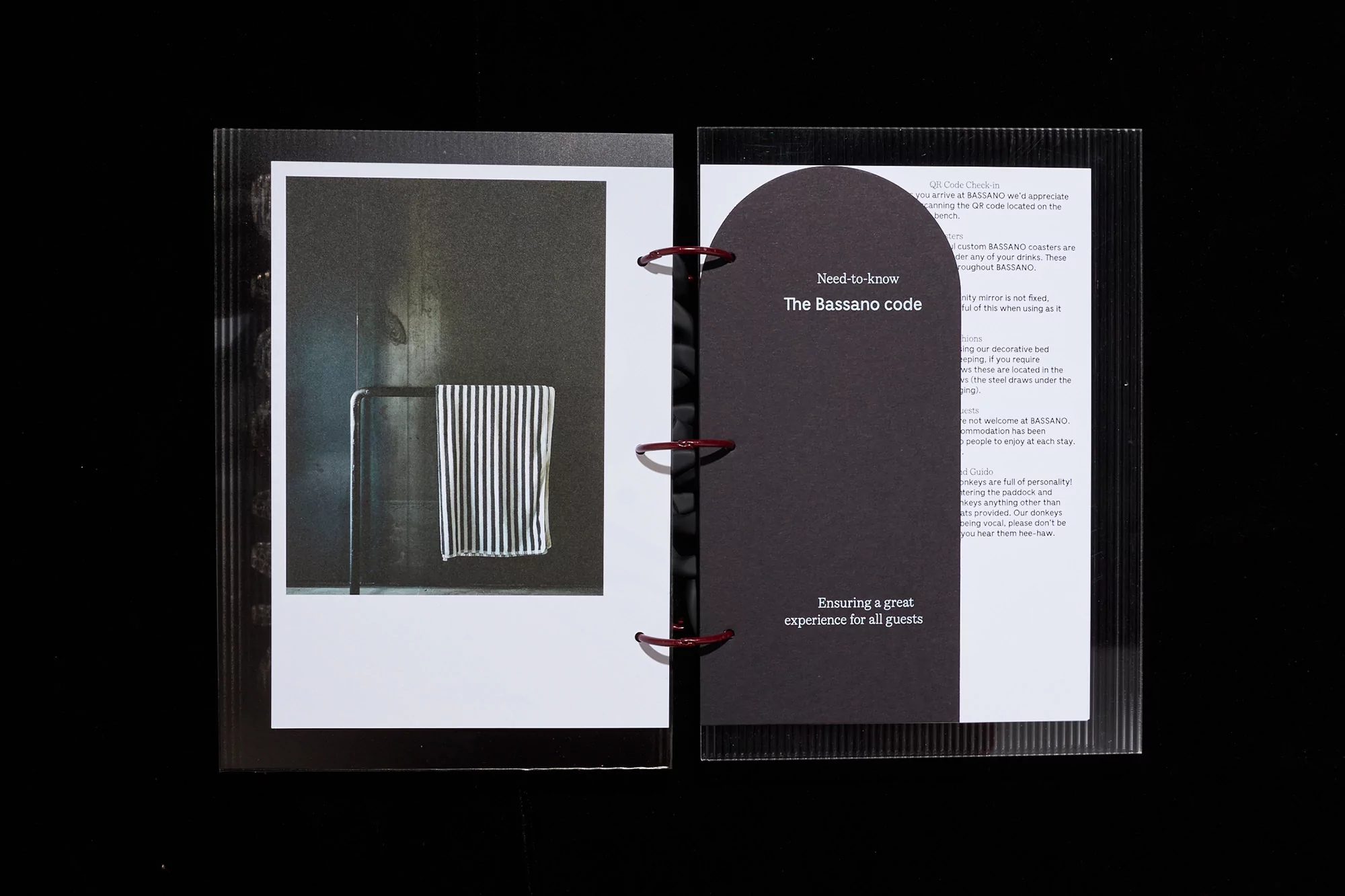 Open ring binder displays a bathroom photograph with a striped towel; information about The Bassano code is also visible.
