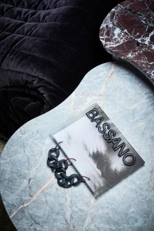 Bassano brand identity design featuring a notebook with black chain details resting on a marble table.