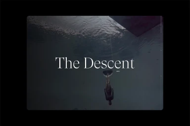 Freediver descending underwater in dark open water captured from below with typography overlay reading The Descent