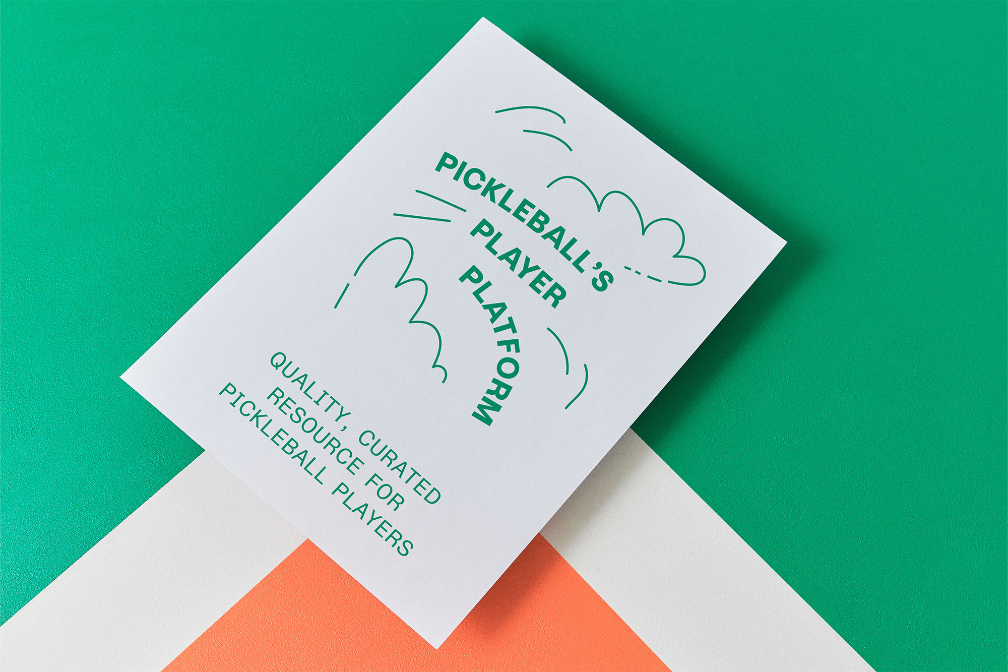 Close-up of a white card with green stylized text for a pickleball platform, set against green, white, and orange geometric background.