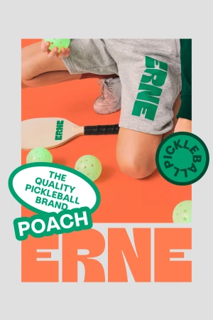 Promotional image of a pickleball set featuring gray athletic shorts, pickleball paddles, and several pickleballs against an orange backdrop.