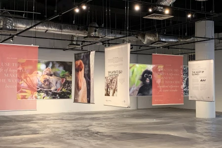 Exhibition space featuring multiple suspended vertical banners displaying wildlife photographs and text in a large hall.