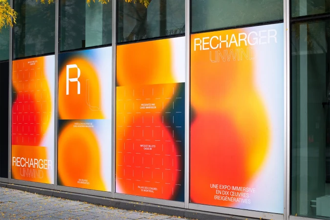 Exterior glass windows featuring vibrant gradient orange and yellow branded window graphics for Recharger Unwind.