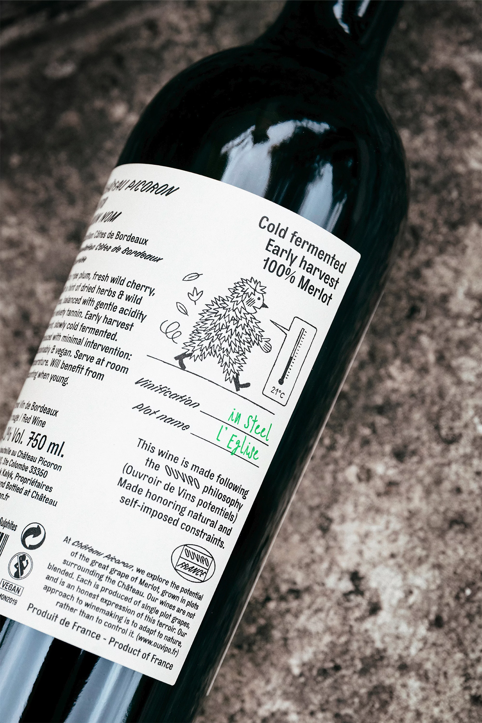 A close-up shot of a dark glass wine bottle with a detailed white label featuring text and an illustration of a hedgehog.