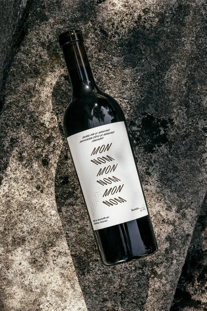 Wine bottle with typographic label resting diagonally on textured stone surface outdoors