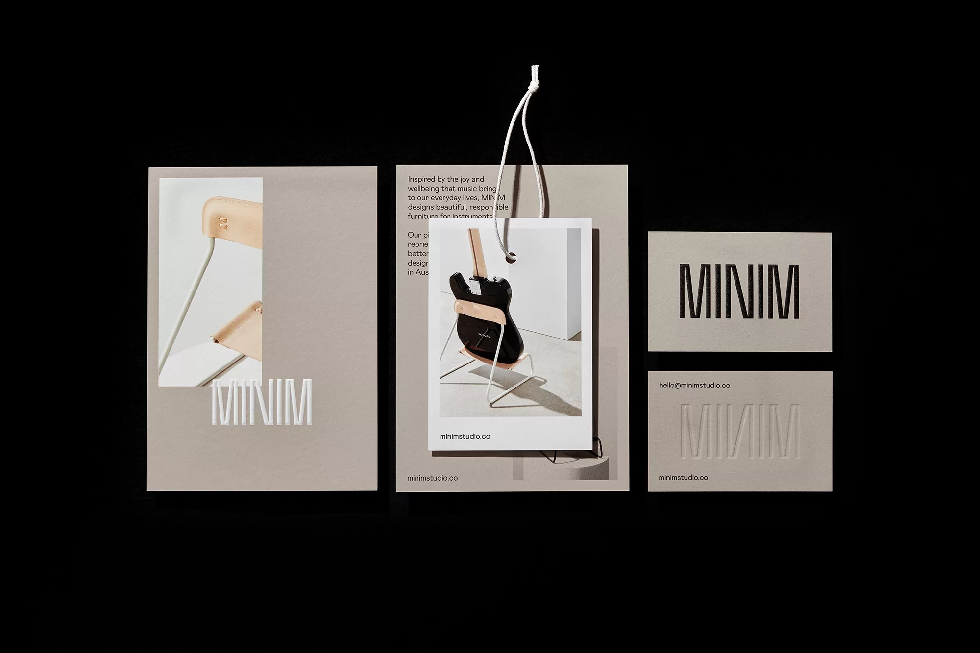 Promotional shot featuring a minimalist chair, guitar, and business cards, all displaying the 'MINIM' logo on a neutral background.