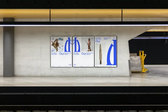 Subway station features three posters advertising the Ötzi exhibition with images of the Iceman and artifacts on a platform.