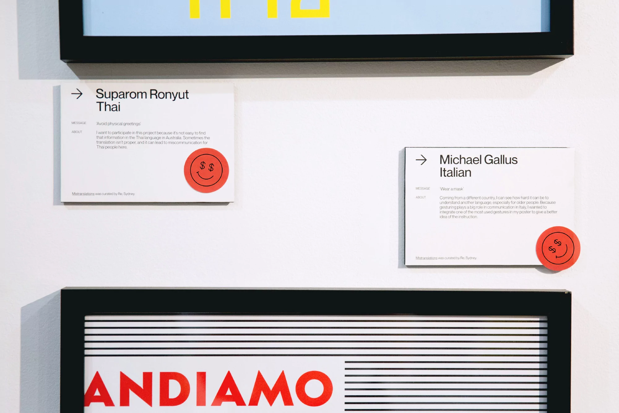Artwork displays framed text posters with cultural messages and graphic elements on a white wall in a gallery setting.