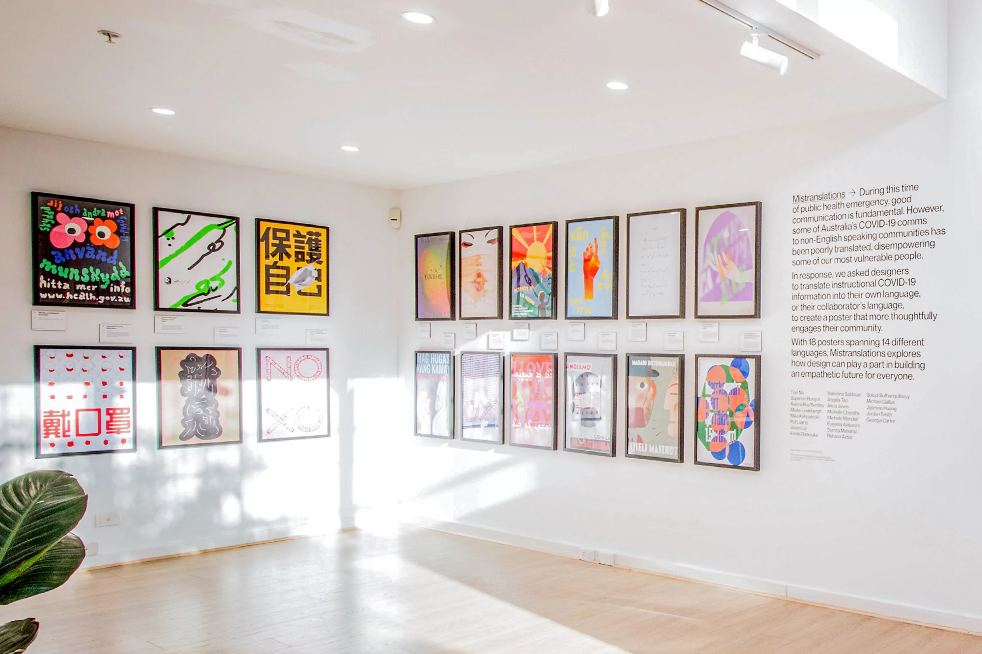 Indoor art gallery with framed colorful posters on white walls, showcasing diverse designs and messages; bright and airy aesthetic.