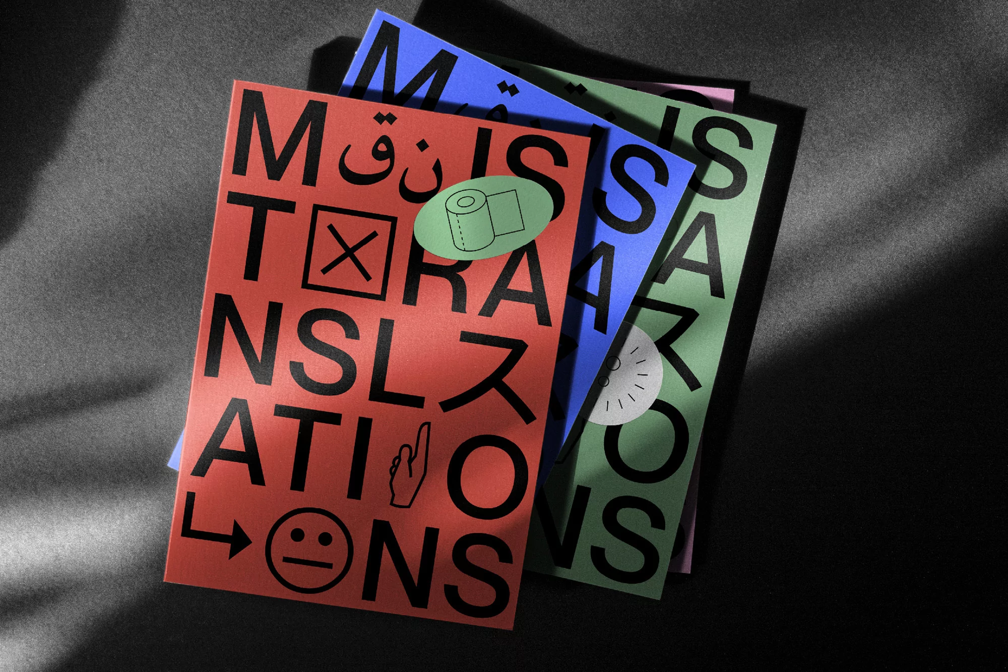 Stack of colorful graphic design books titled 'Translations' with bold typography and a contemporary aesthetic on a dark surface.
