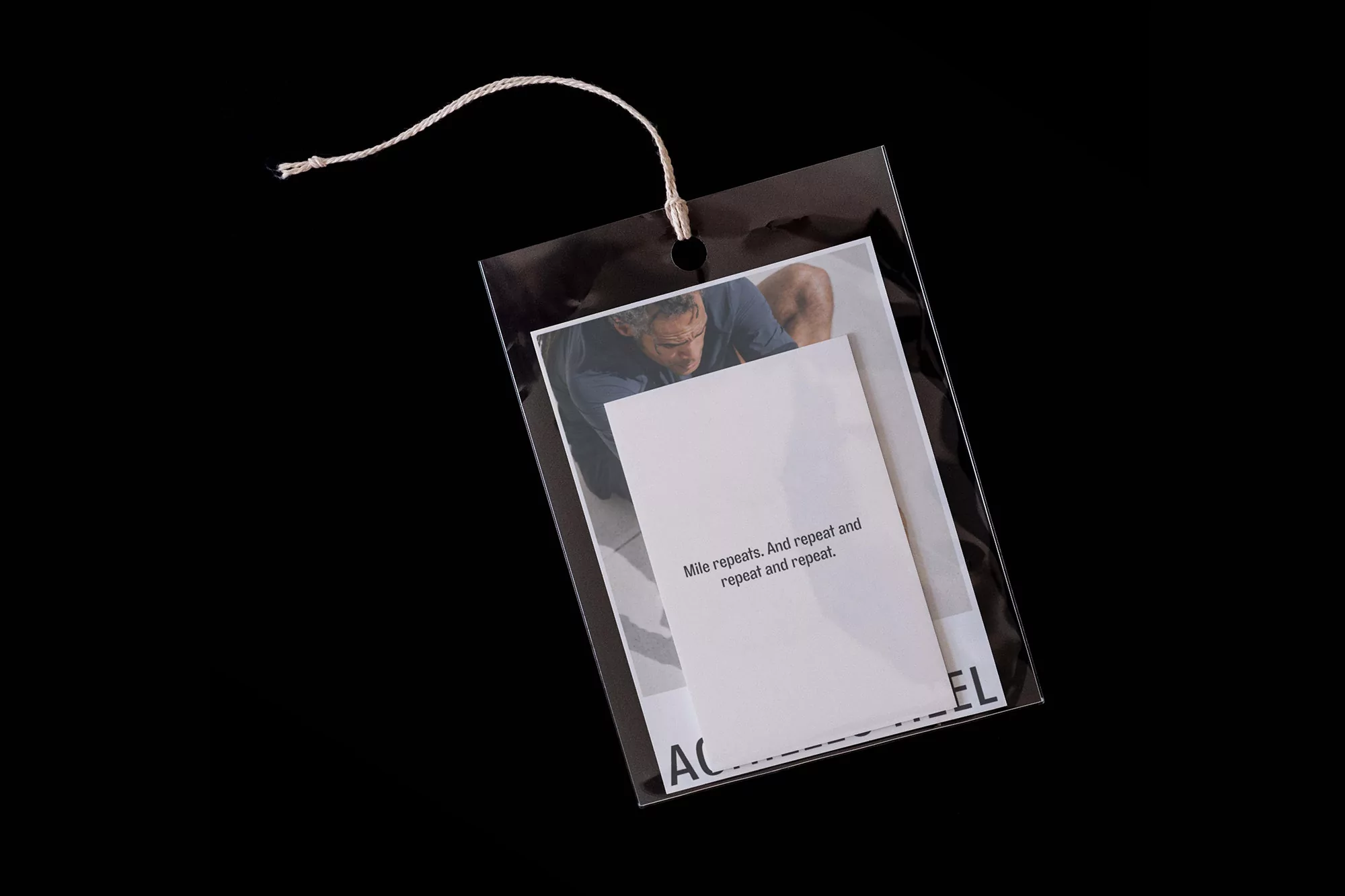 Close-up of a glossy tag featuring a man and text, presented against a stark black backdrop for a minimalist effect.