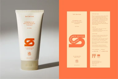 Soft Services skincare tube product packaging next to brand identity collateral on orange