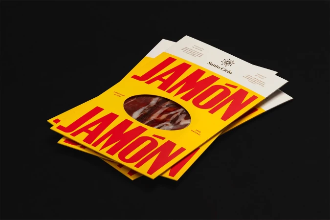 Packaged Jamón Ibérico product on a black surface, featuring a bright yellow package design with bold red lettering, product is visible.