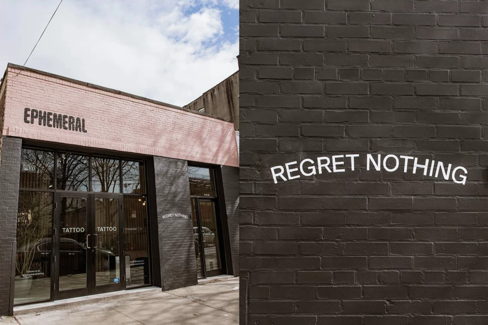 Outdoor shot of the Ephemeral tattoo studio with brick walls and bold lettering, expressing an edgy, modern aesthetic in daylight.