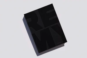 Black book with debossed typography resting on a clean white surface casting a sharp shadow.