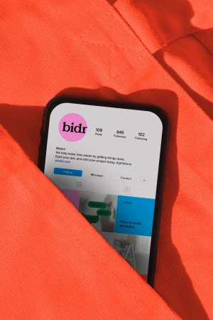 A smartphone displaying a social media profile inside an orange fabric pocket
