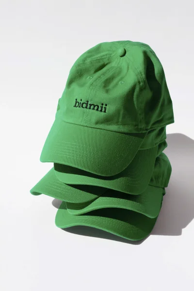 A stack of four vibrant green baseball caps with black embroidered text on a plain white background.