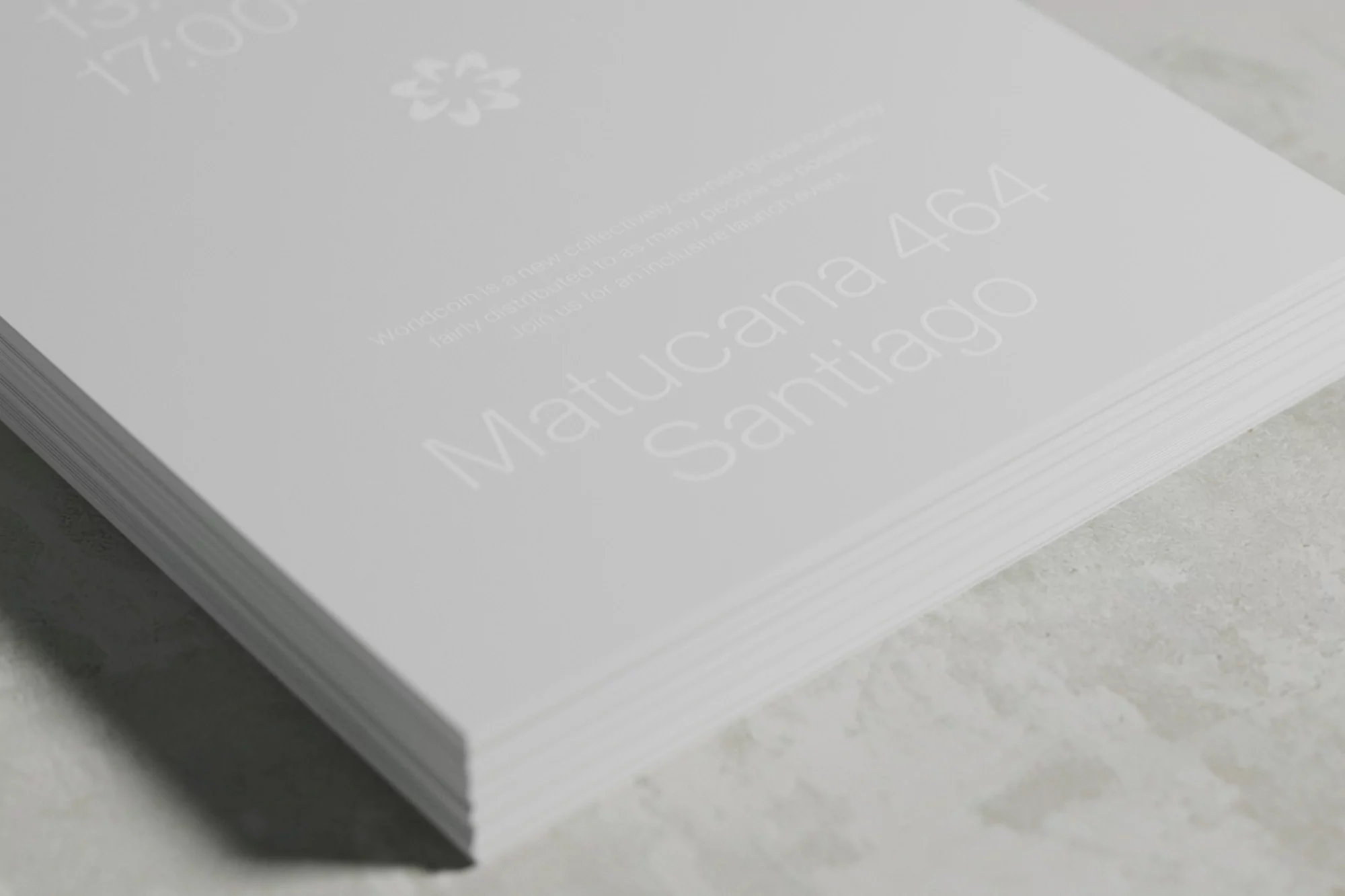 Stack of white paper with light text featuring 'Matucana 464 Santiago' and floral watermark in bright, minimalist, indoor composition.