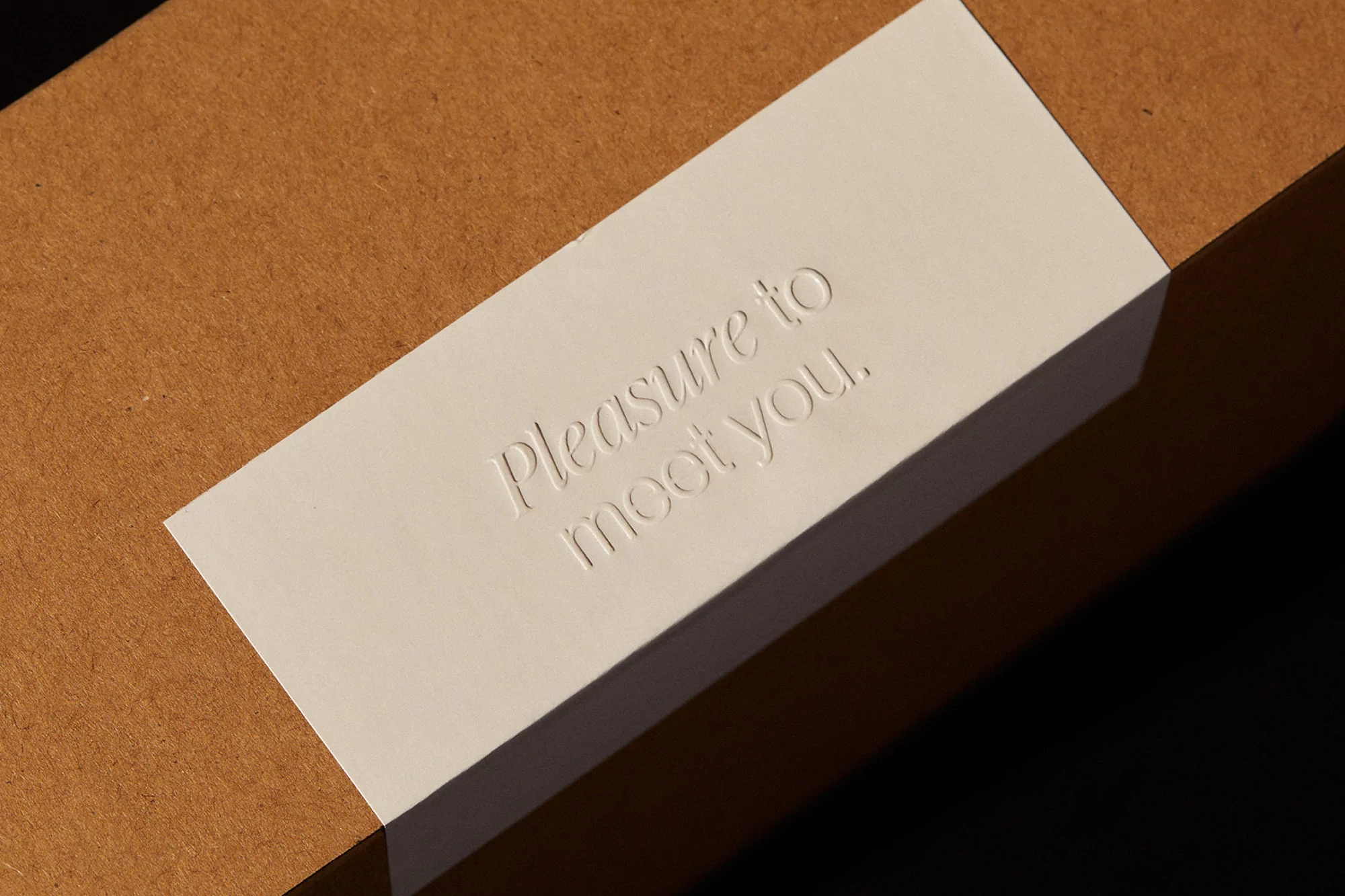 Close-up of a cardboard box with a white label that reads, 'Pleasure to meet you' in a clean, minimalist font, capturing a sense of greeting.