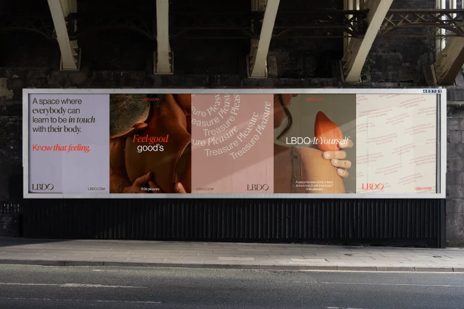 Billboard ad featuring LBDO products and body positivity messaging under a bridge with grey textured ground. Promotes self-discovery.