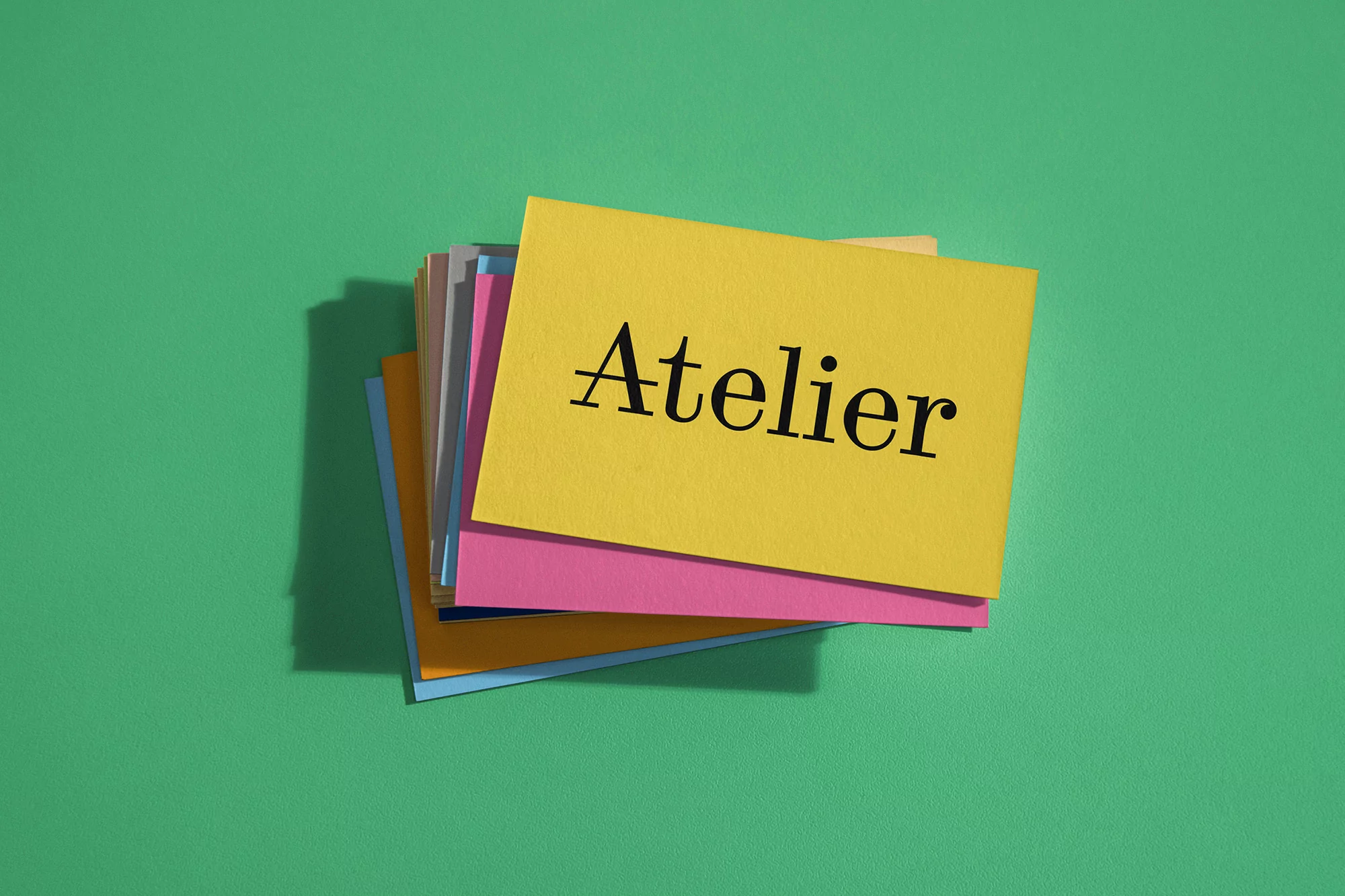 Stack of colorful Atelier cards on green background creates a vibrant, artistic feel, perfect for creative projects and workshop themes.