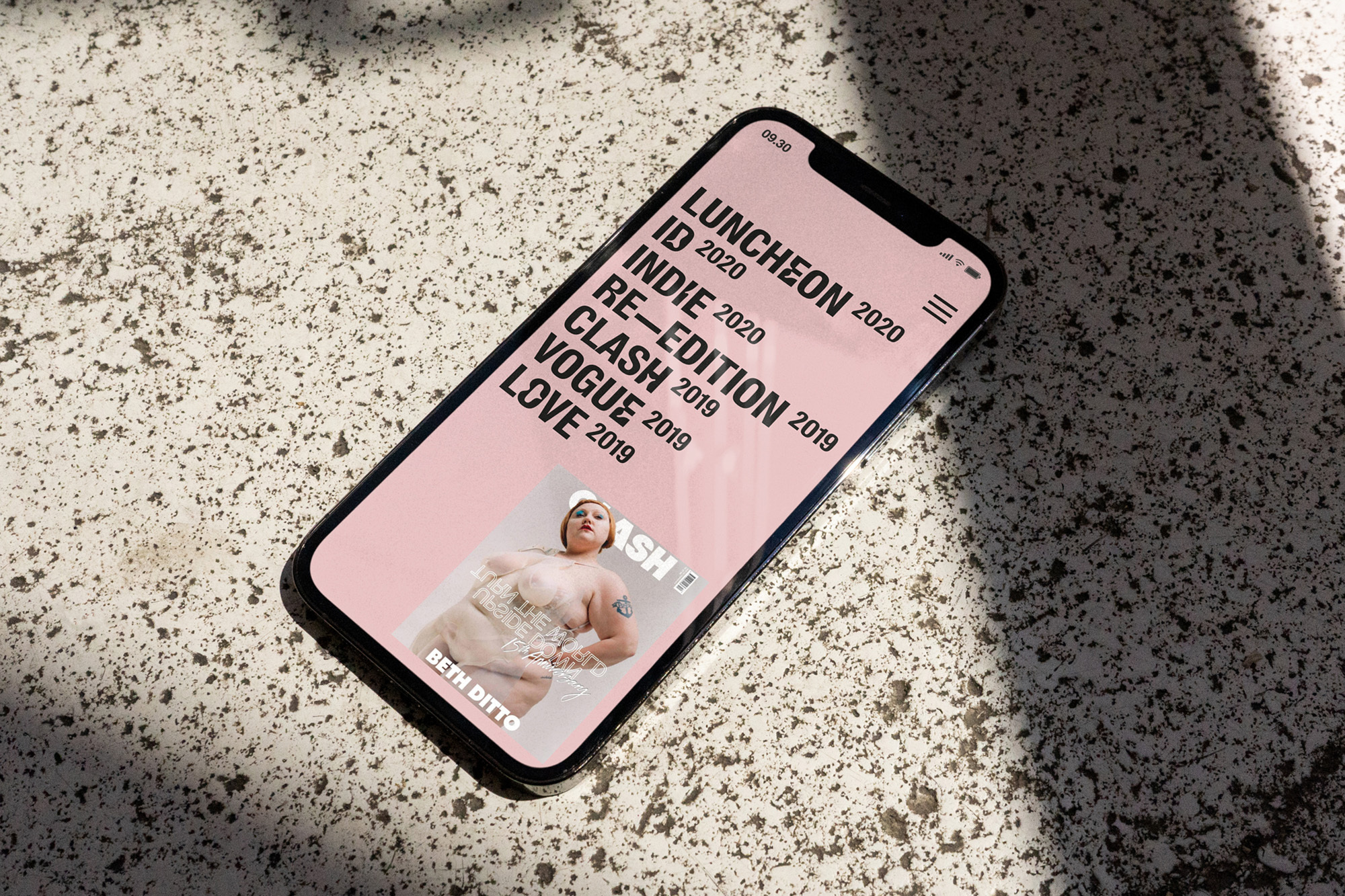 Smartphone screen displays magazine cover with Beth Ditto on textured surface in natural light.