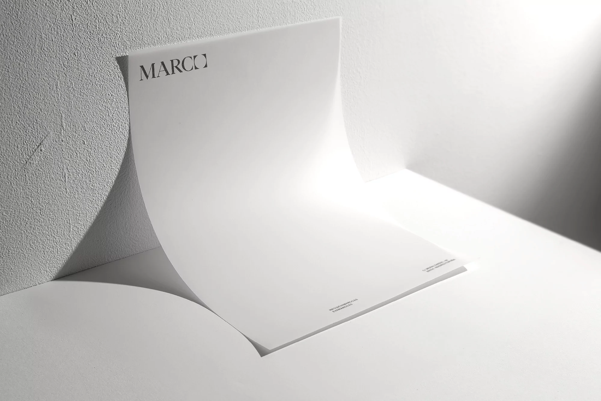 White paper with the text 'MARCO' displayed in clean indoor lighting. A minimalist and bright presentation for graphic design.