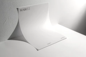 Curved white letterhead stationery paper with the text Marco printed in the top corner against a textured white wall backdrop.