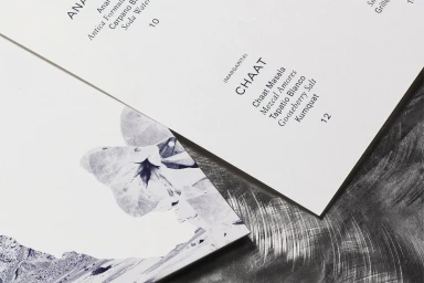 Printed menus with typography and blue botanical imagery on textured metal surface