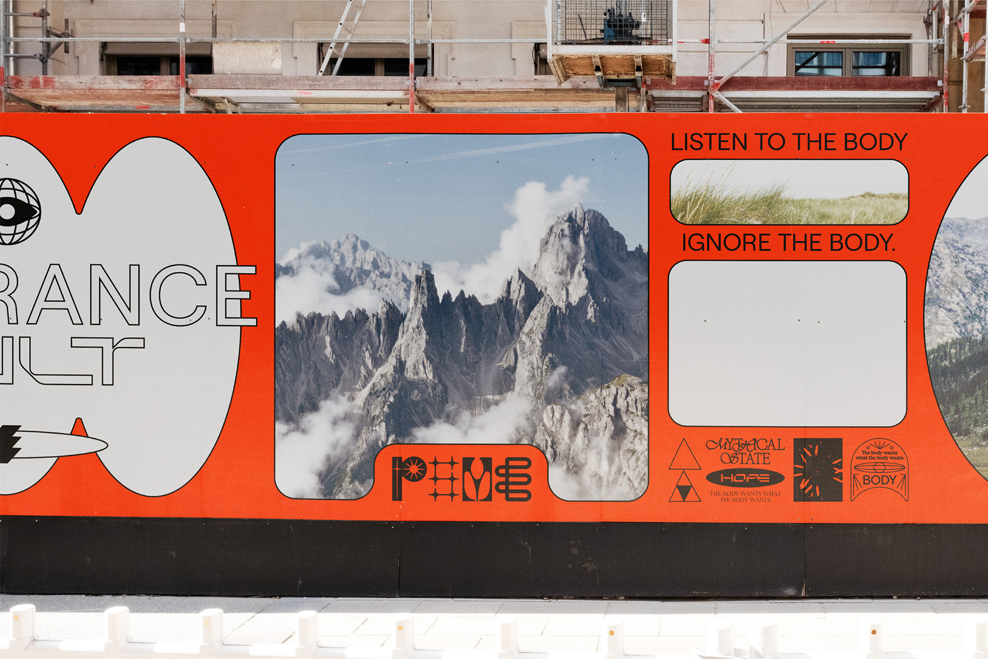 Outdoor hoarding featuring mountain range, grass, and text art with an orange background, promoting themes of body awareness and hope.