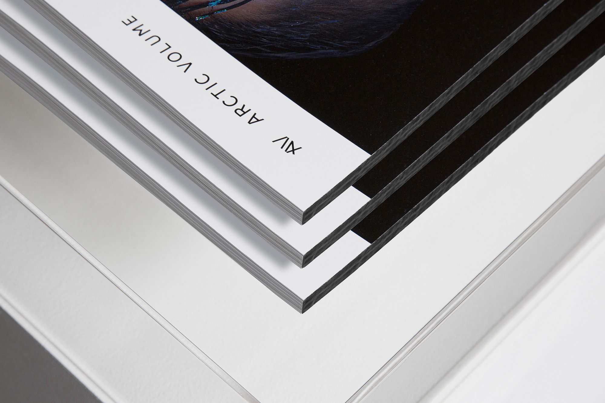 Stack of magazines or booklets, showing a close-up of the page edges and cover art against a plain white background, showcasing graphic design.