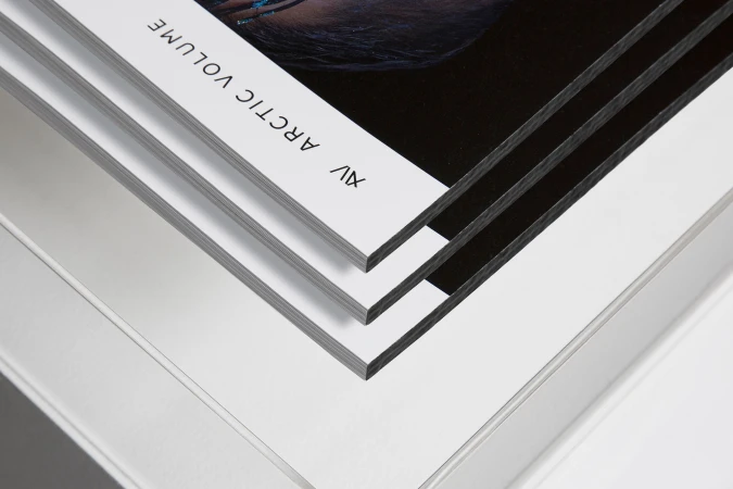 Stack of magazines or booklets, showing a close-up of the page edges and cover art against a plain white background, showcasing graphic design.