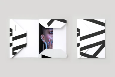 Mockup of an open and closed white paper folder featuring bold black diagonal geometric stripe patterns and a close-up portrait insert.