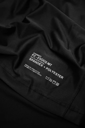 Close-up of black garment fabric featuring a white printed label with the words GARMENT, SPANDEX, and POLYESTER, plus care symbols.
