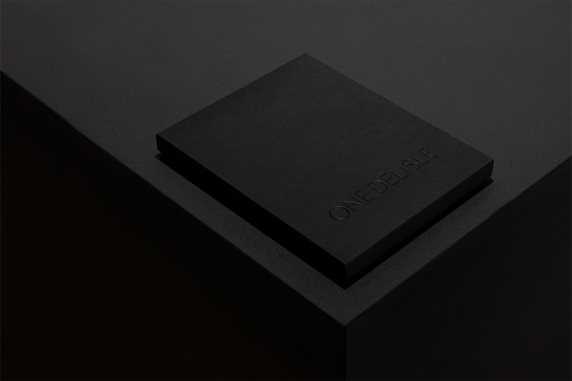 Elevated shot of a sleek, black box on a textured surface, highlighted by low-key lighting that accentuates its minimalist design.