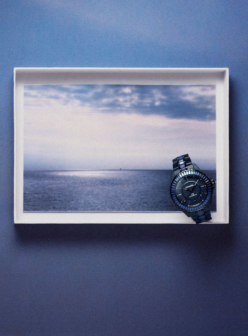 Luxury wristwatch on a white tray, showcasing a captivating photograph of an ocean landscape, highlighted by a complementary blue background.