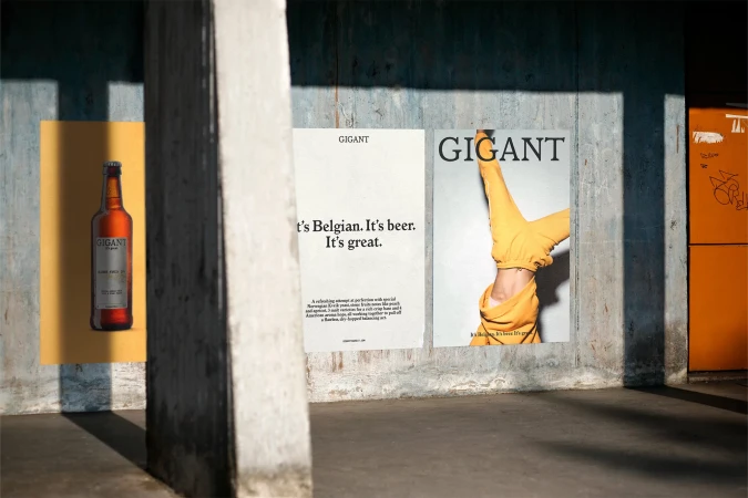 Outdoor advertising campaign featuring a beer bottle poster, alongside posters with text and a person in a yellow outfit on a textured wall.