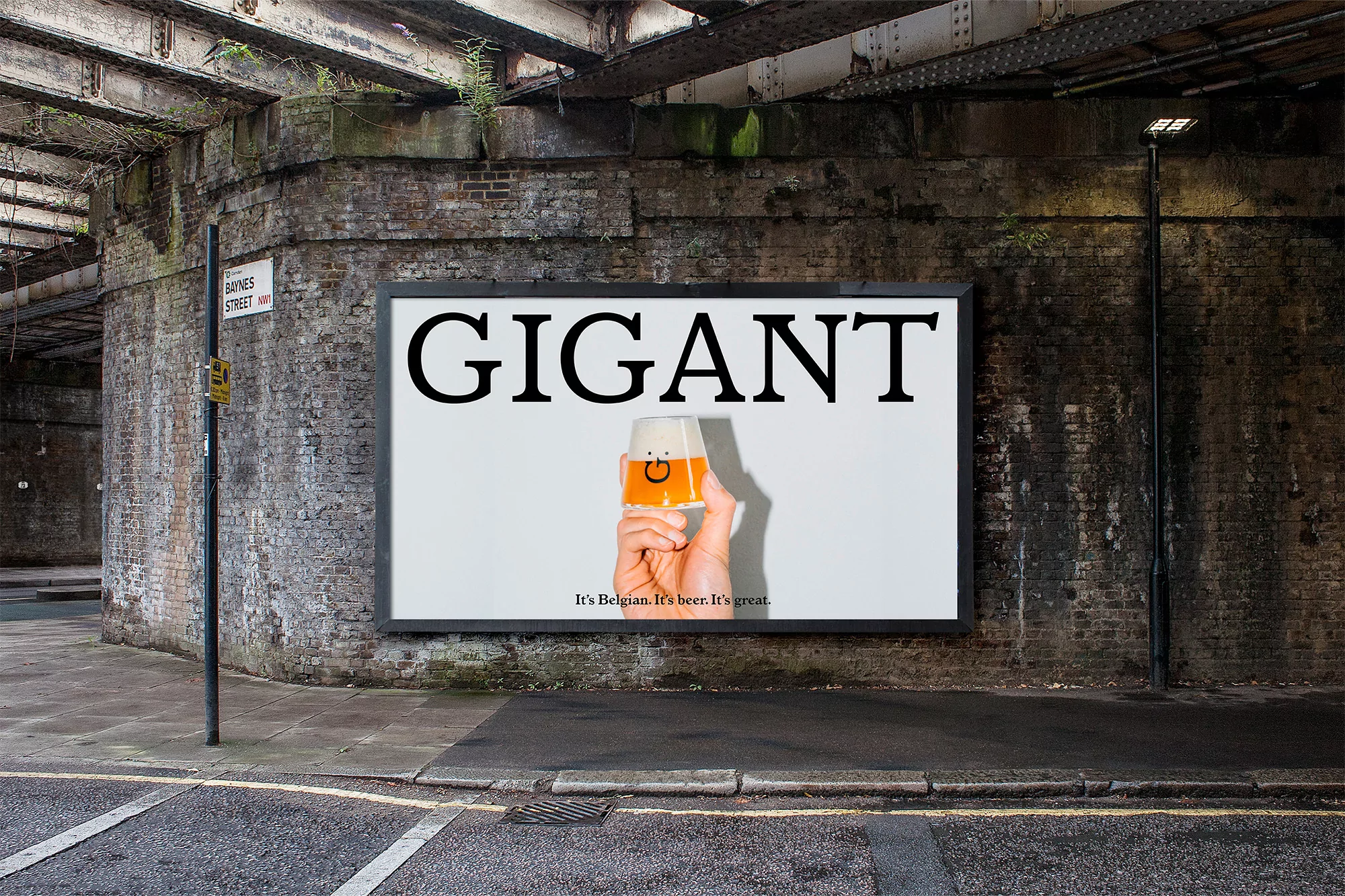 Outdoor advertising billboard displaying an image of a hand holding a beer glass, placed under a weathered railway bridge.