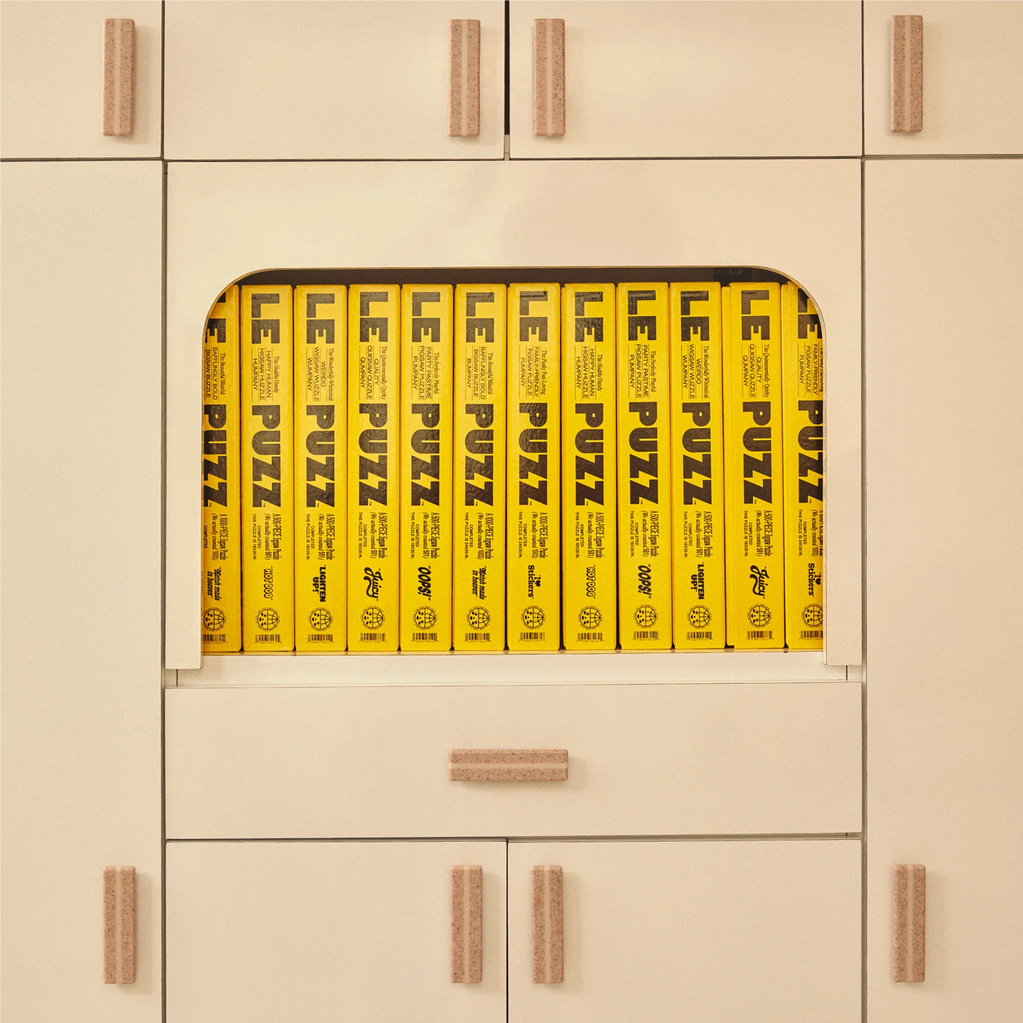 Close-up of a built-in off-white cabinet and drawer unit filled with a collection of yellow game boxes with bold black lettering.