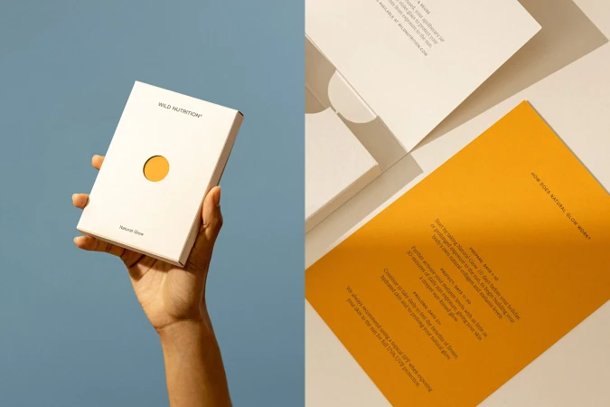 Hand holds Wild Nutrition supplement box with orange circle, alongside informational cards with instructions on how to use supplements.